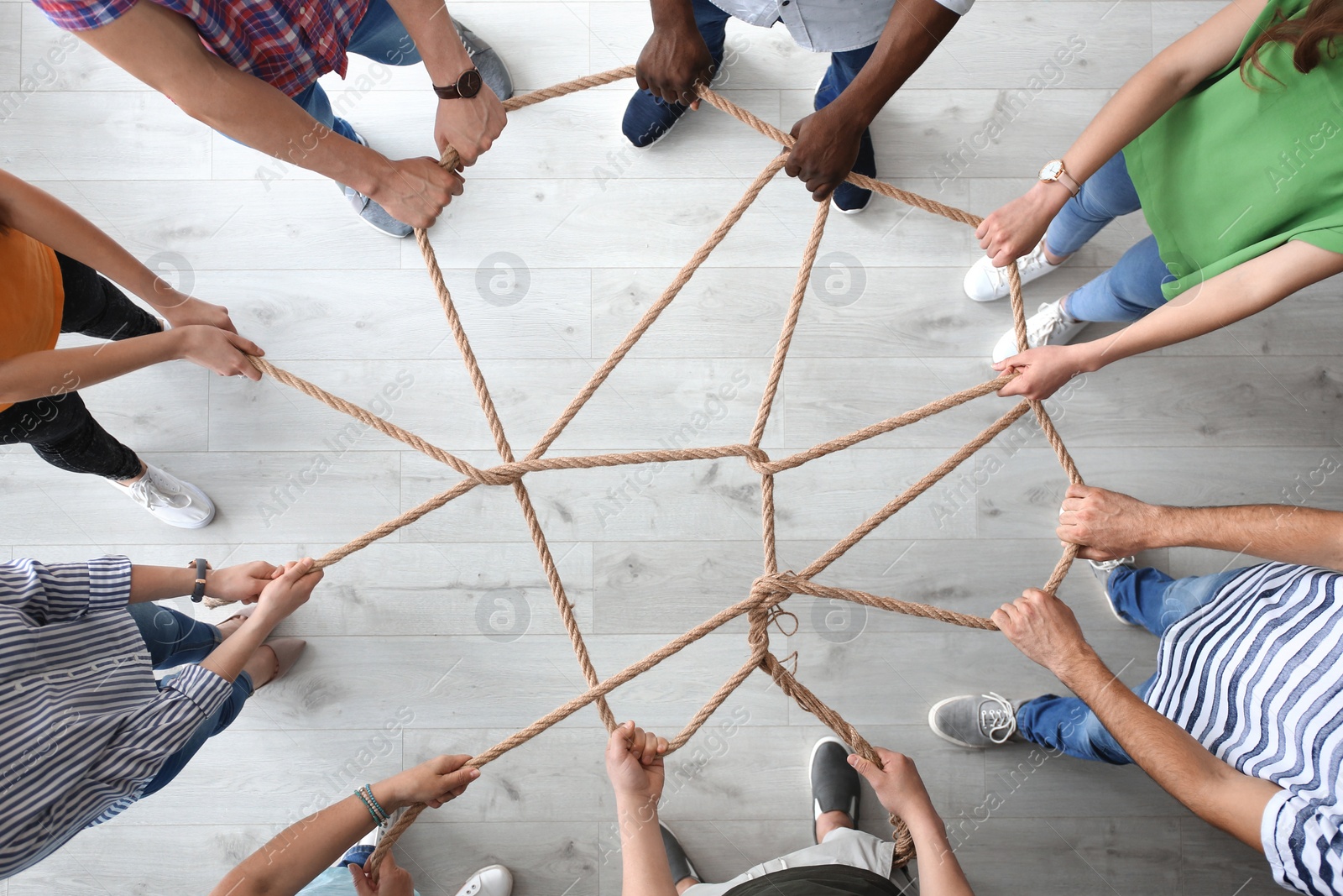 Photo of People holding rope together indoors, top view. Unity concept