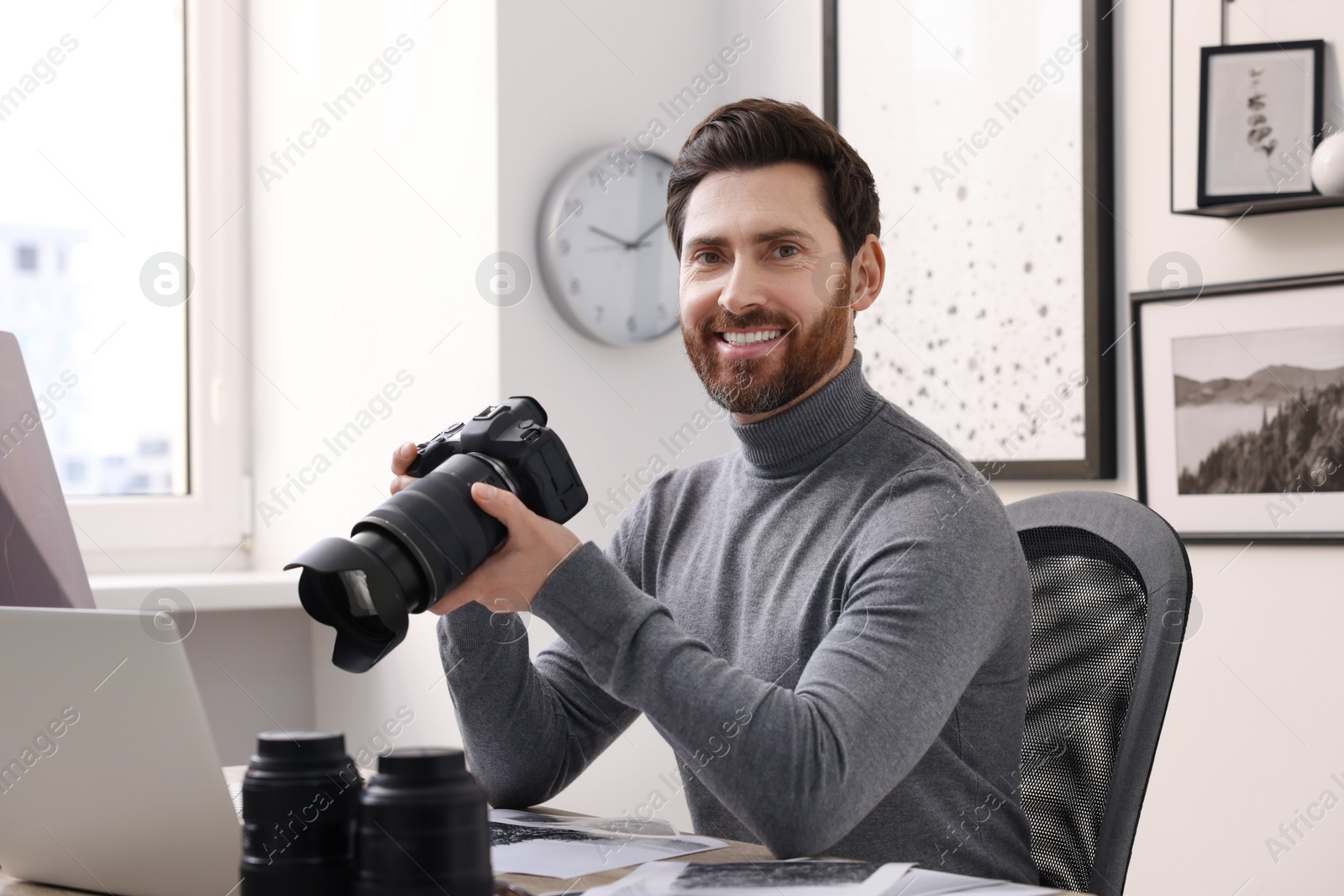 Photo of Professional photographer with digital camera at table in office