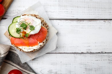 Photo of Crunchy buckwheat cakes with salmon, poached egg and cucumber slices on white wooden table, flat lay. Space for text
