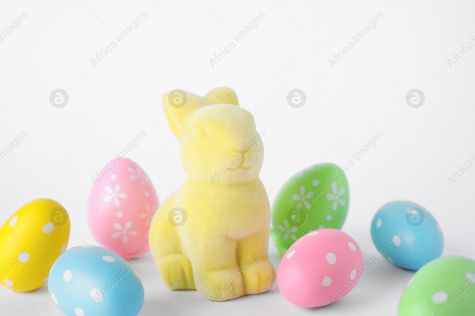 Photo of Easter bunny toy and dyed eggs on white background