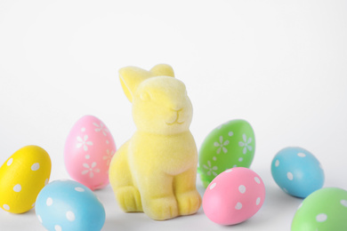 Photo of Easter bunny toy and dyed eggs on white background