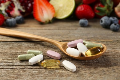 Photo of Different vitamin pills and fresh fruits on wooden table