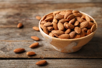 Photo of Tasty organic almond nuts in bowl on table. Space for text