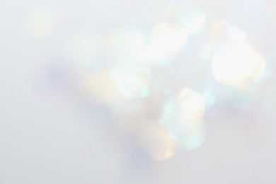 Blurred view of shiny lights on white background. Bokeh effect