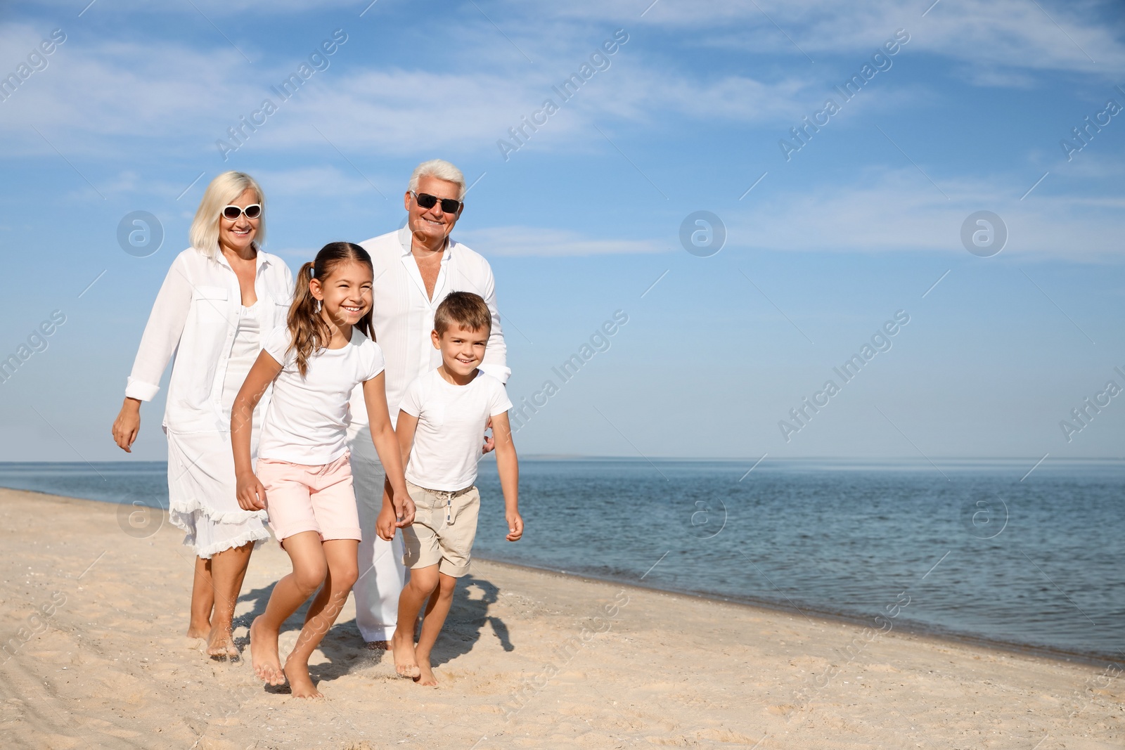 Photo of Cute little children with grandparents spending time together on sea beach