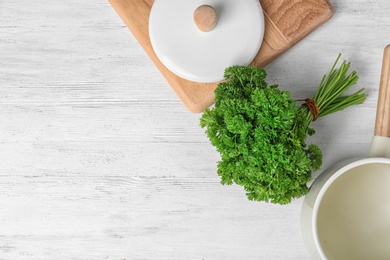 Flat lay composition with fresh green parsley and space for text on white wooden background