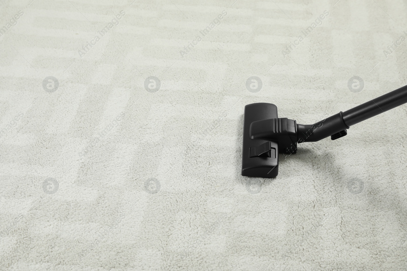 Photo of Removing dirt from white carpet with modern vacuum cleaner. Space for text