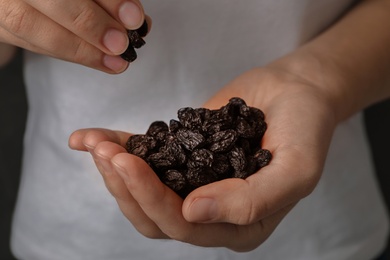 Photo of Woman holding raisins on black background, closeup