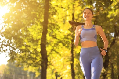 Photo of Attractive sporty woman jogging in beautiful park on sunny day. Space for text