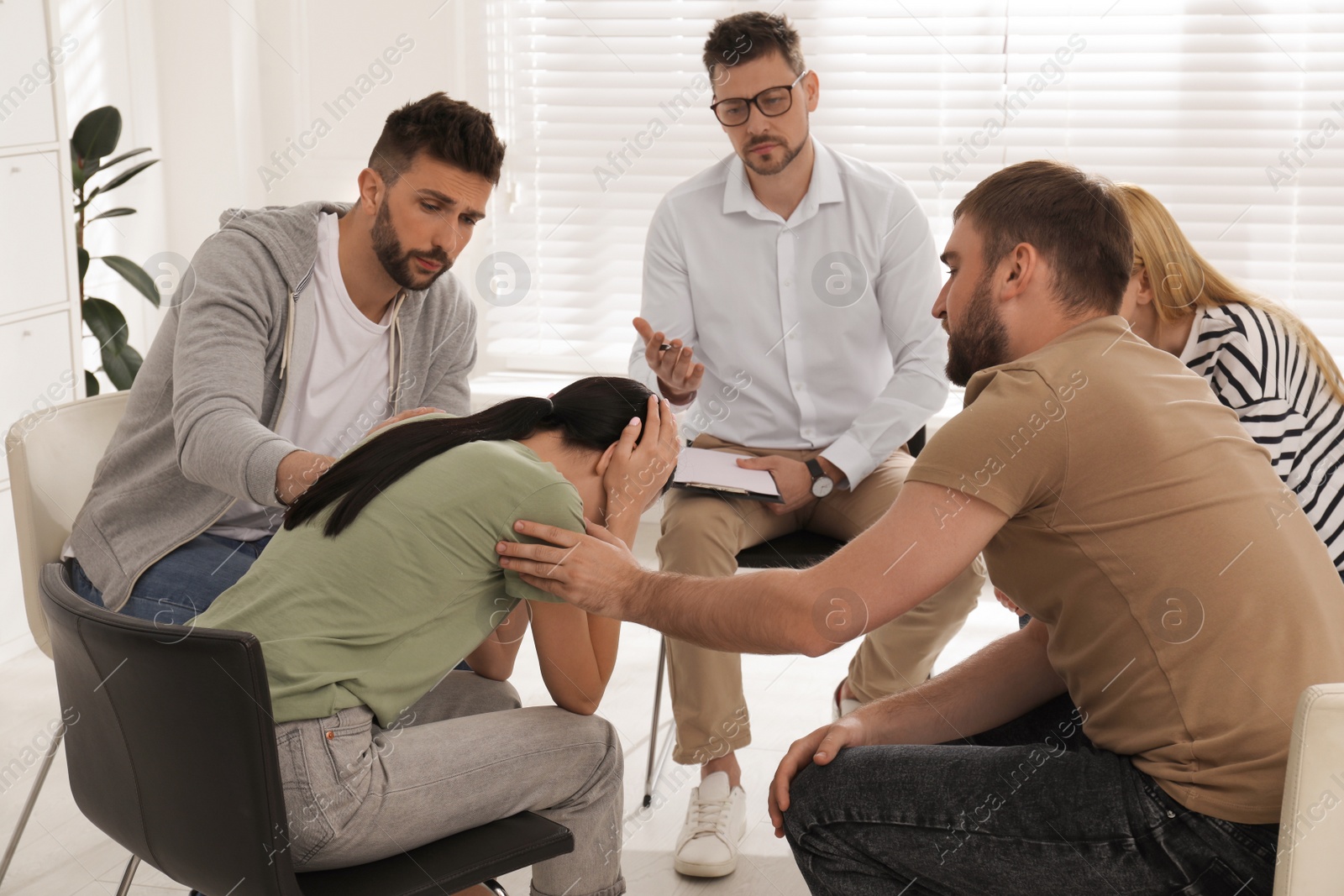 Photo of Psychotherapist working with group of drug addicted people at therapy session indoors