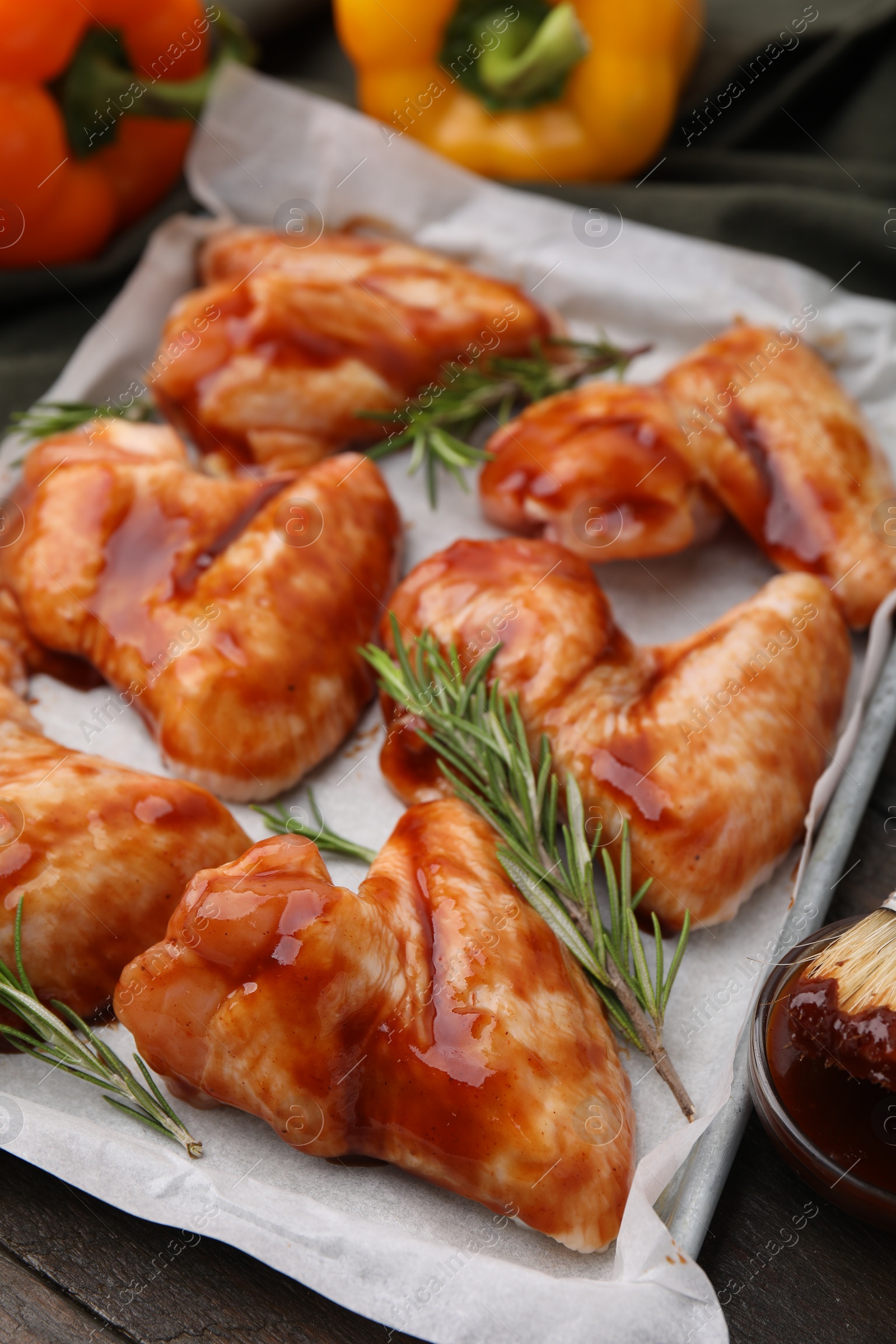 Photo of Raw marinated chicken wings and rosemary on wooden table, closeup