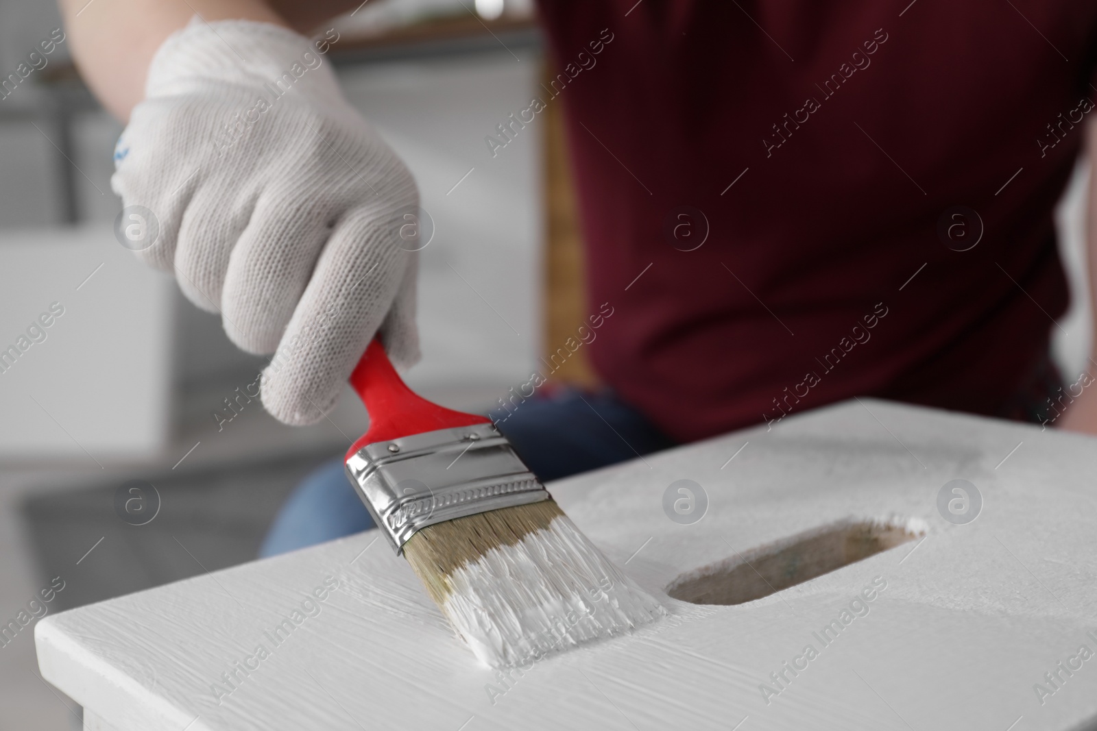 Photo of Man using brush to paint bekvam with white dye indoors, closeup