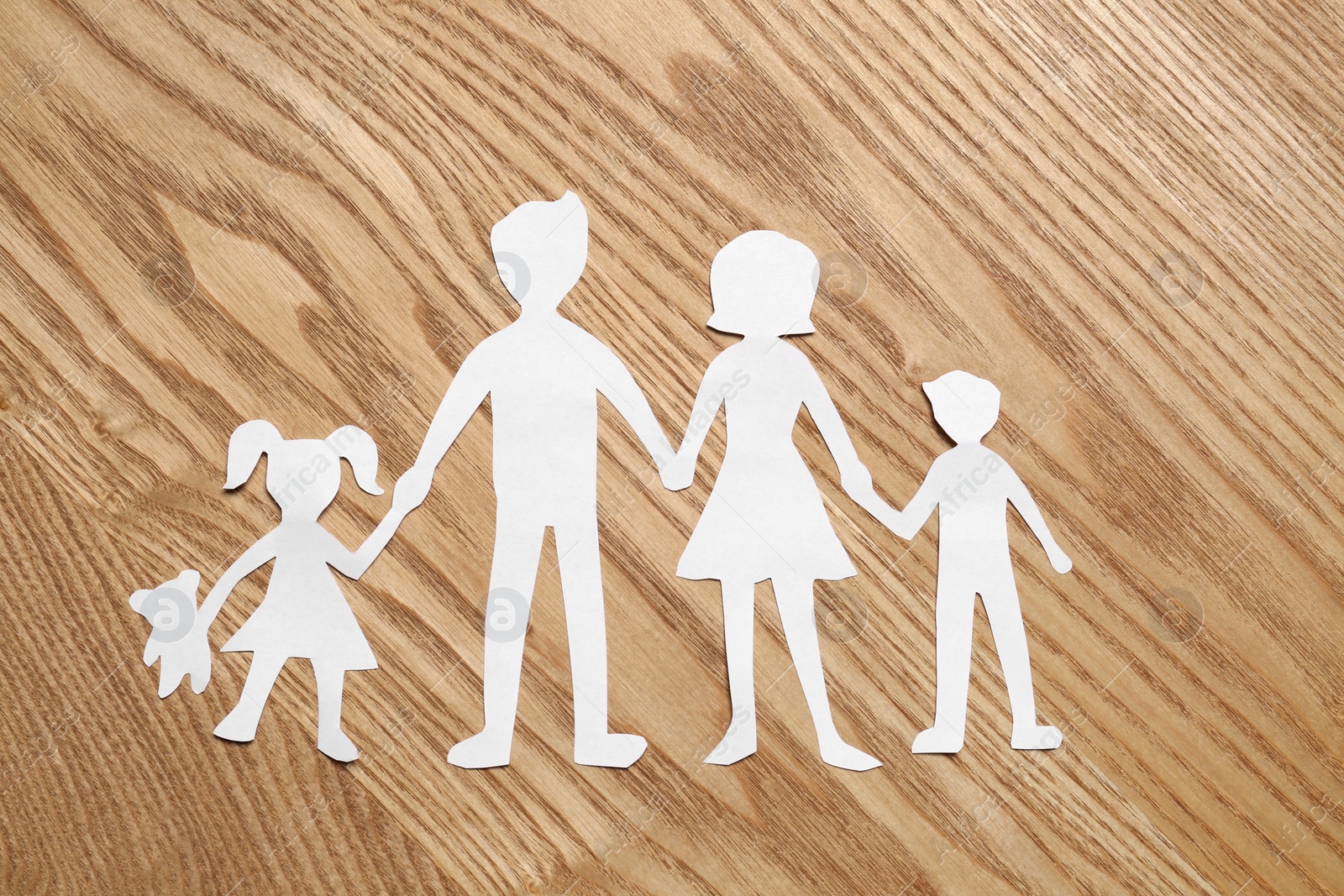 Photo of Family paper cutout on wooden table, top view