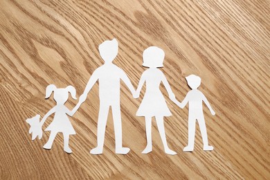 Photo of Family paper cutout on wooden table, top view