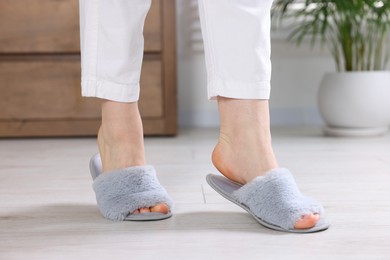 Photo of Woman in grey soft slippers at home, closeup