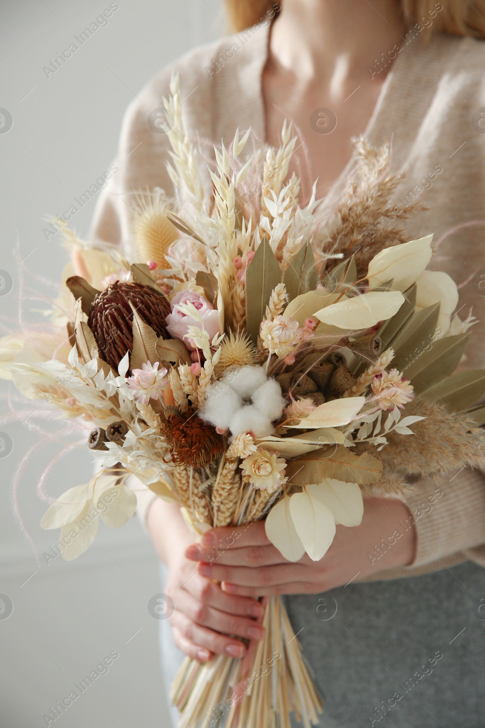 Photo of Woman holding beautiful dried flower bouquet at home, closeup