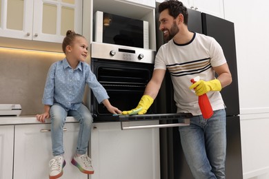 Photo of Spring cleaning. Father and daughter tidying up oven in kitchen together