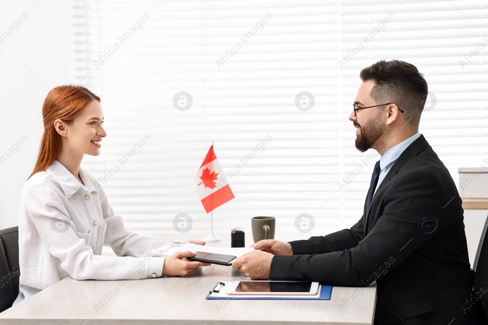Photo of Immigration to Canada. Smiling woman having interview with embassy worker in office