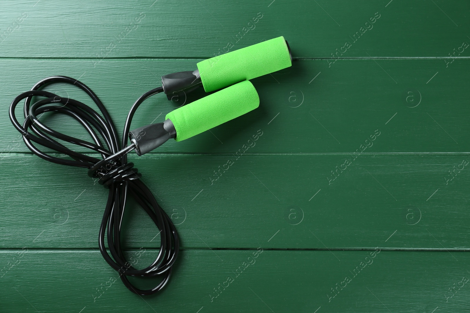 Photo of Skipping rope on green wooden table, top view. Space for text