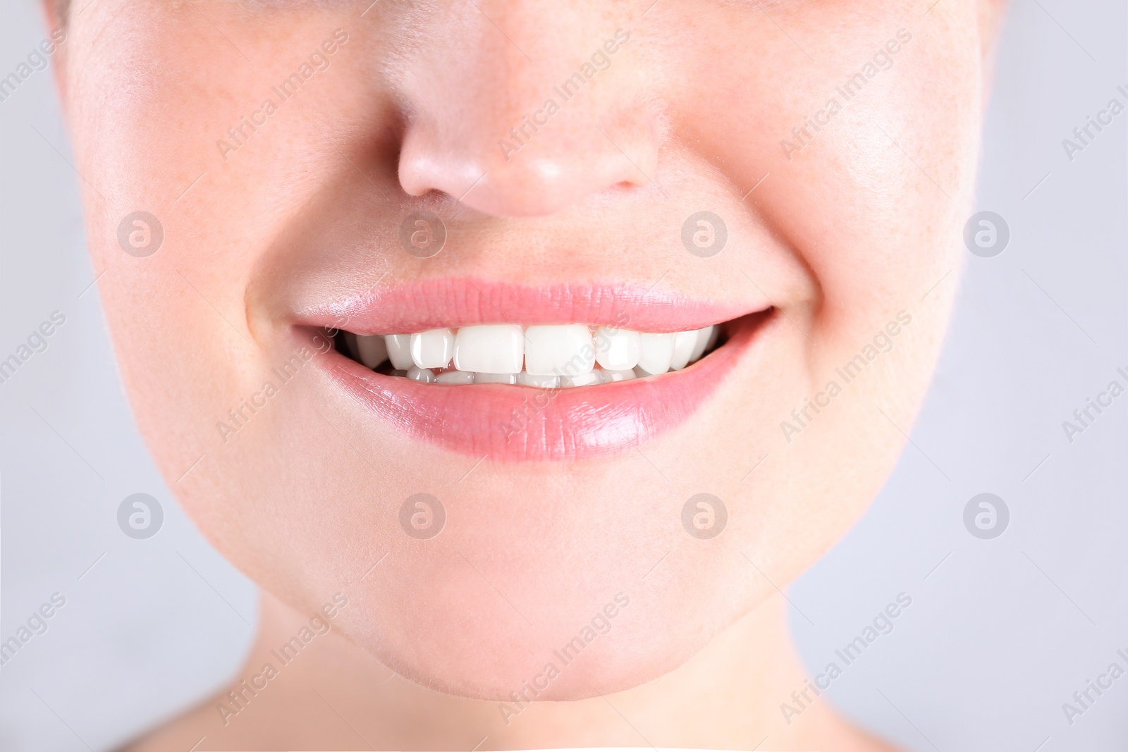 Photo of Young woman with beautiful smile on light background, closeup