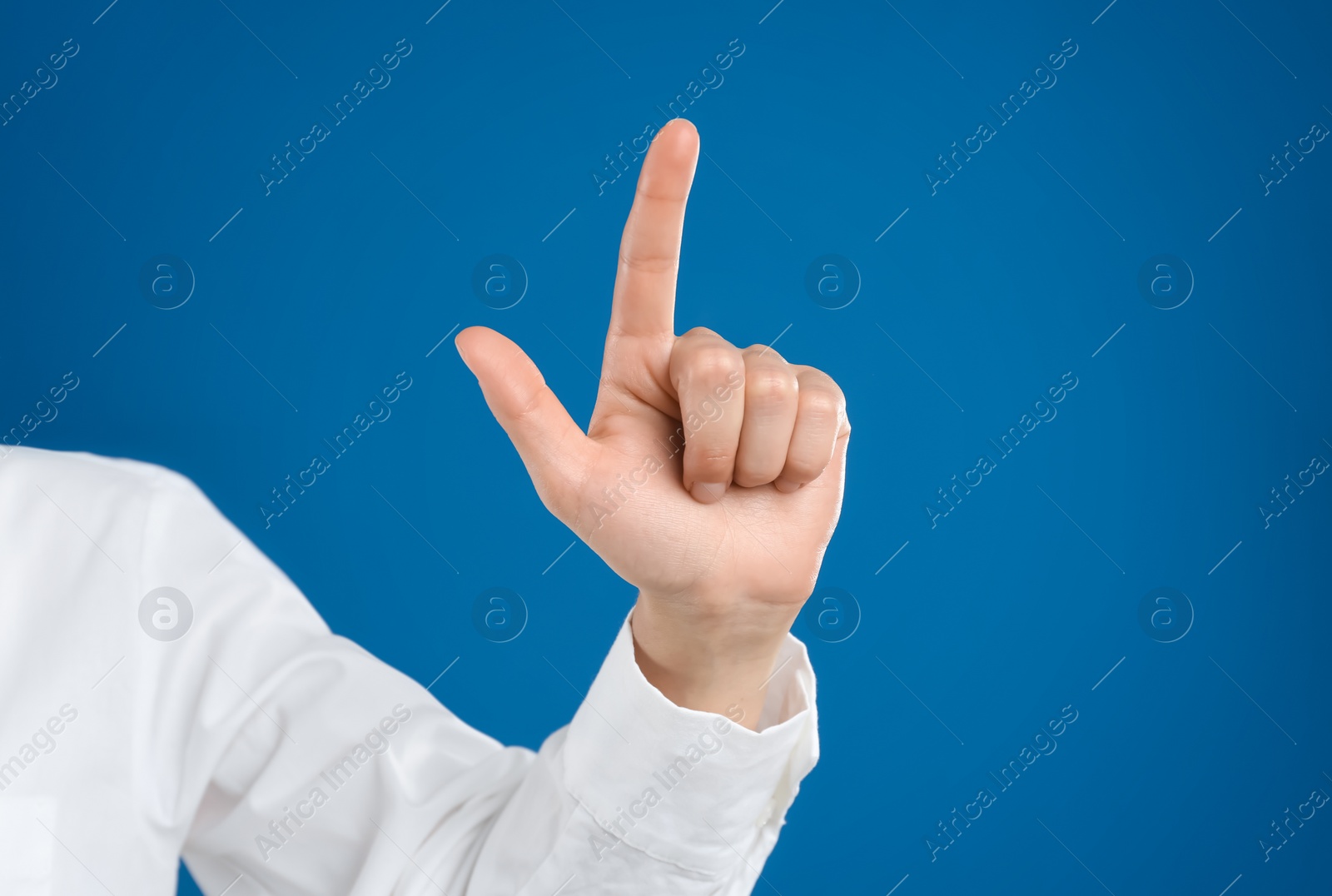 Photo of Young woman touching something against blue background, closeup view