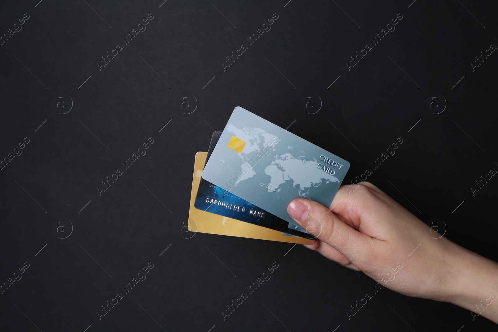 Photo of Woman holding credit cards on black background, closeup