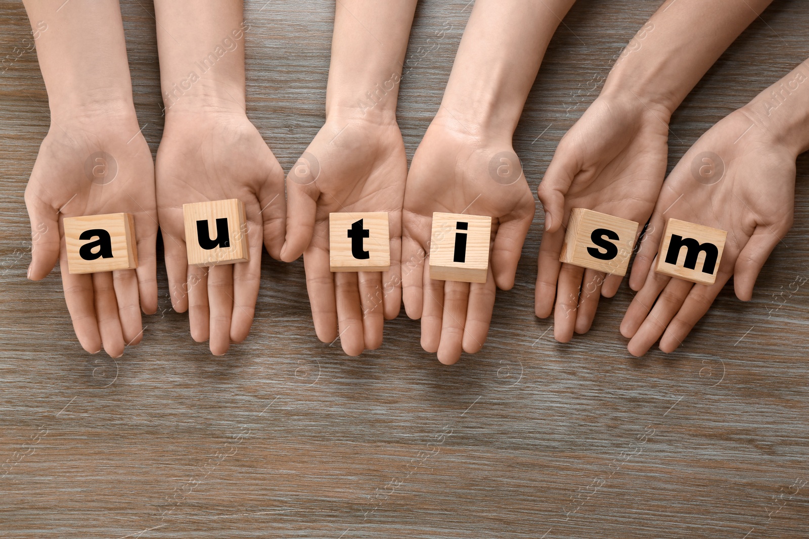 Photo of Group of people holding cubes with word "Autism" on wooden background