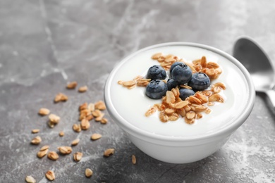 Photo of Bowl with yogurt, berries and granola on gray table