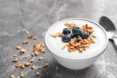 Bowl with yogurt, berries and granola on gray table