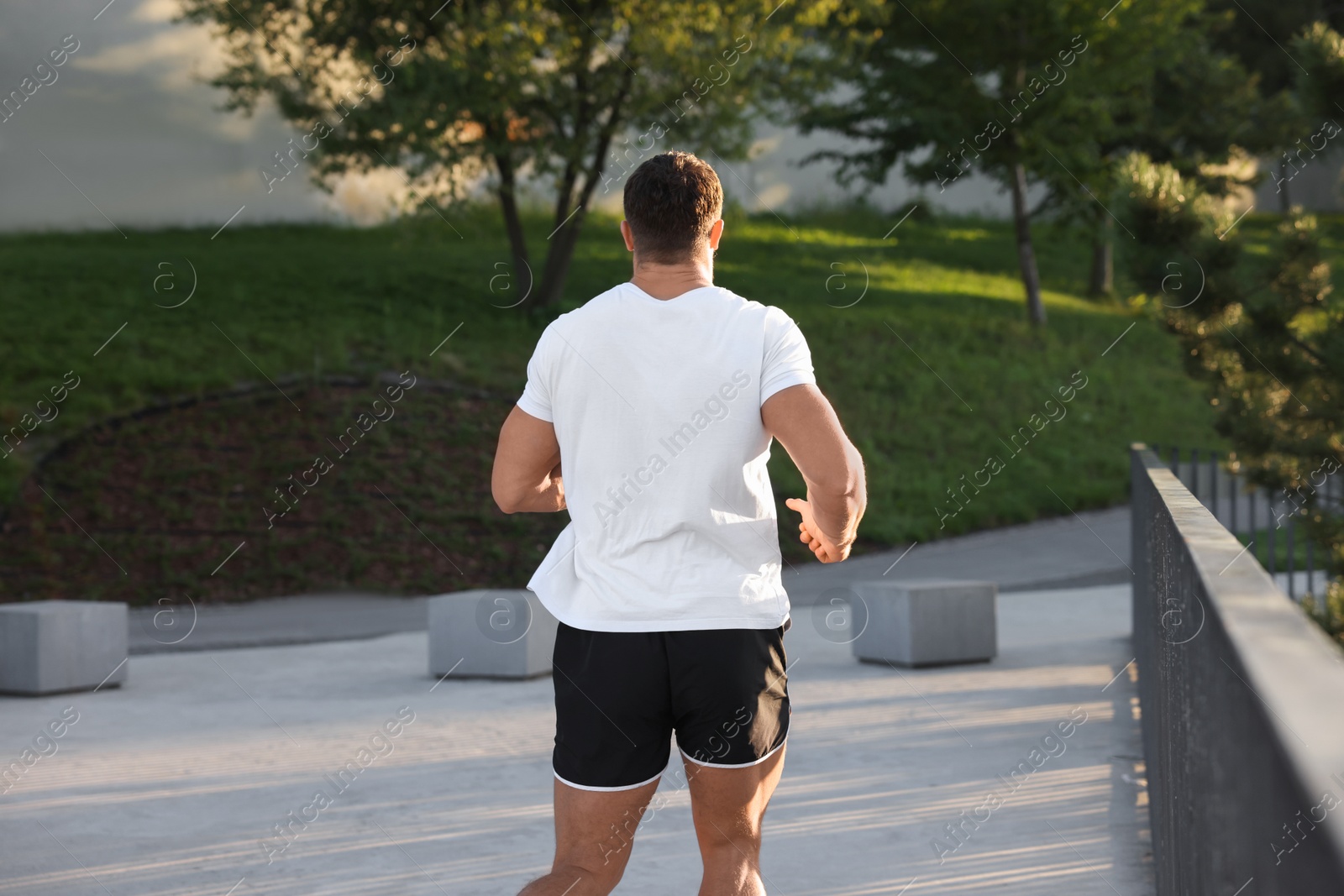 Photo of Man running outdoors on sunny day, back view