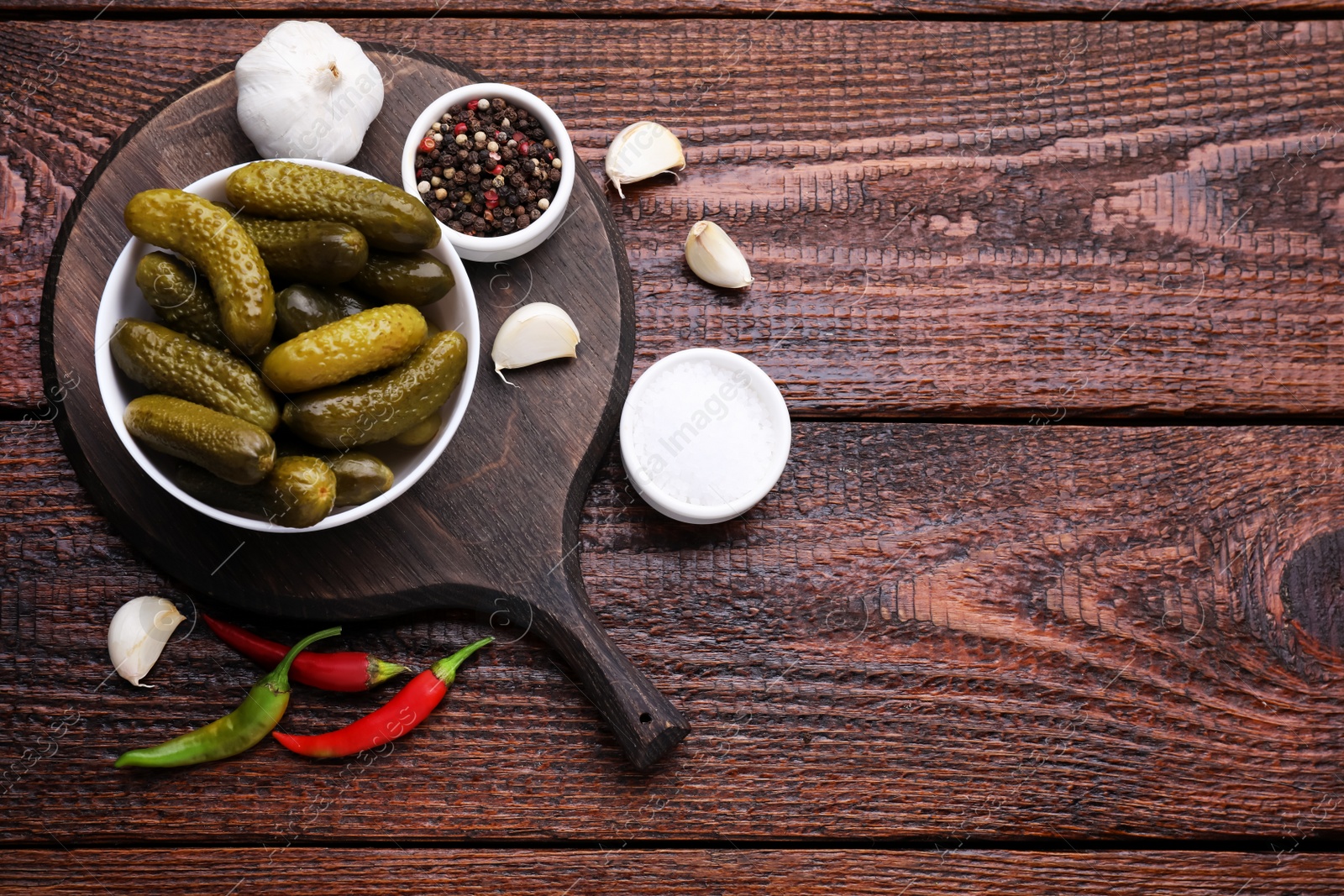 Photo of Pickled cucumbers and ingredients on wooden table, flat lay. Space for text