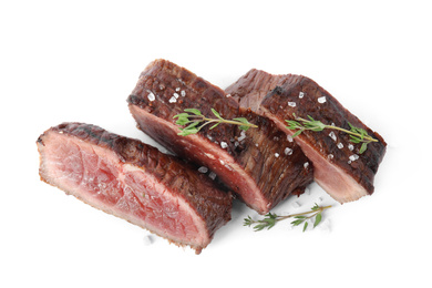 Photo of Delicious sliced beef steak with thyme and salt isolated on white, top view