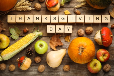 Photo of Cubes with phrase THANKSGIVING DAY, autumn fruits and vegetables on wooden background, flat lay. Happy holiday