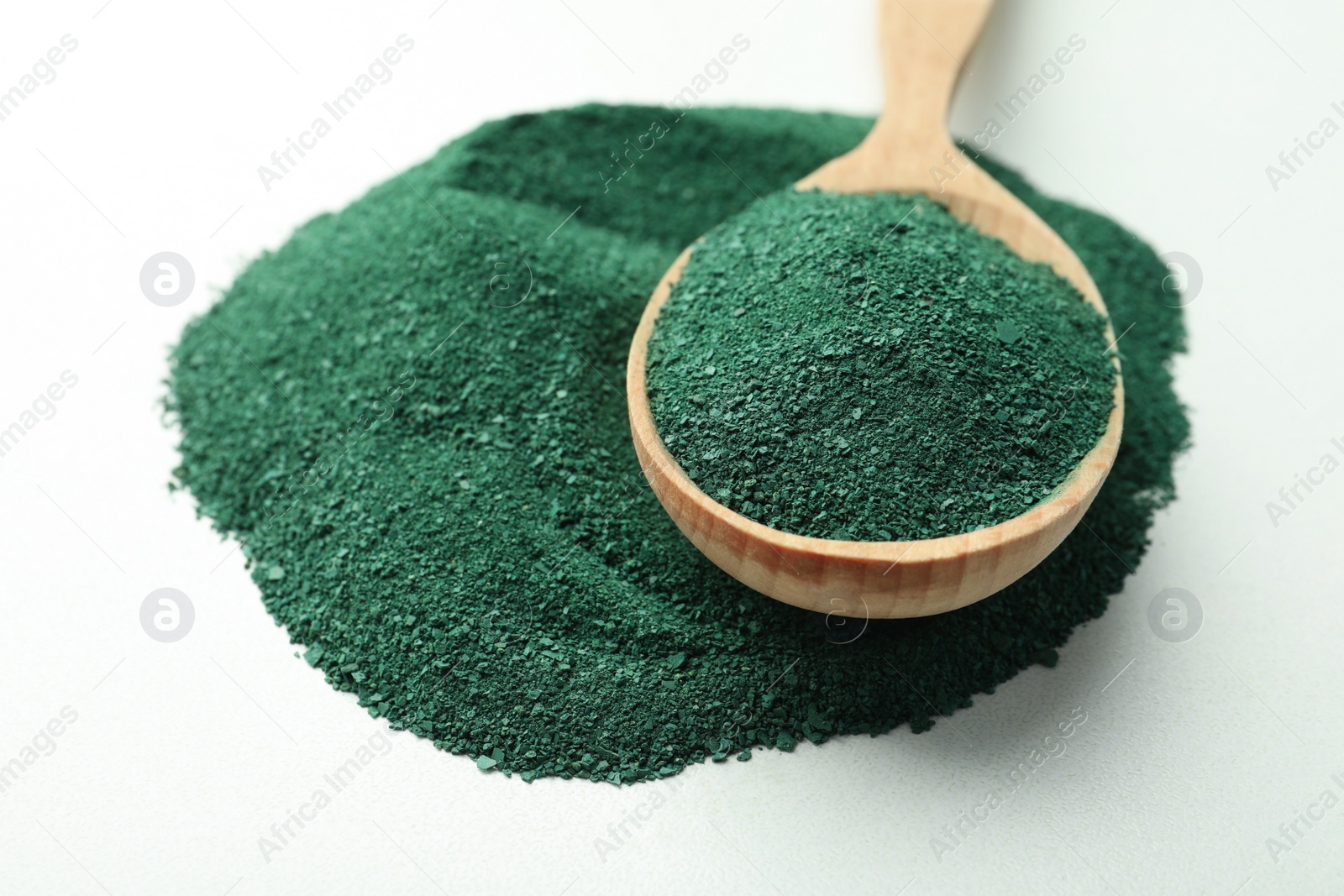 Photo of Spoon with spirulina algae powder on white background, closeup