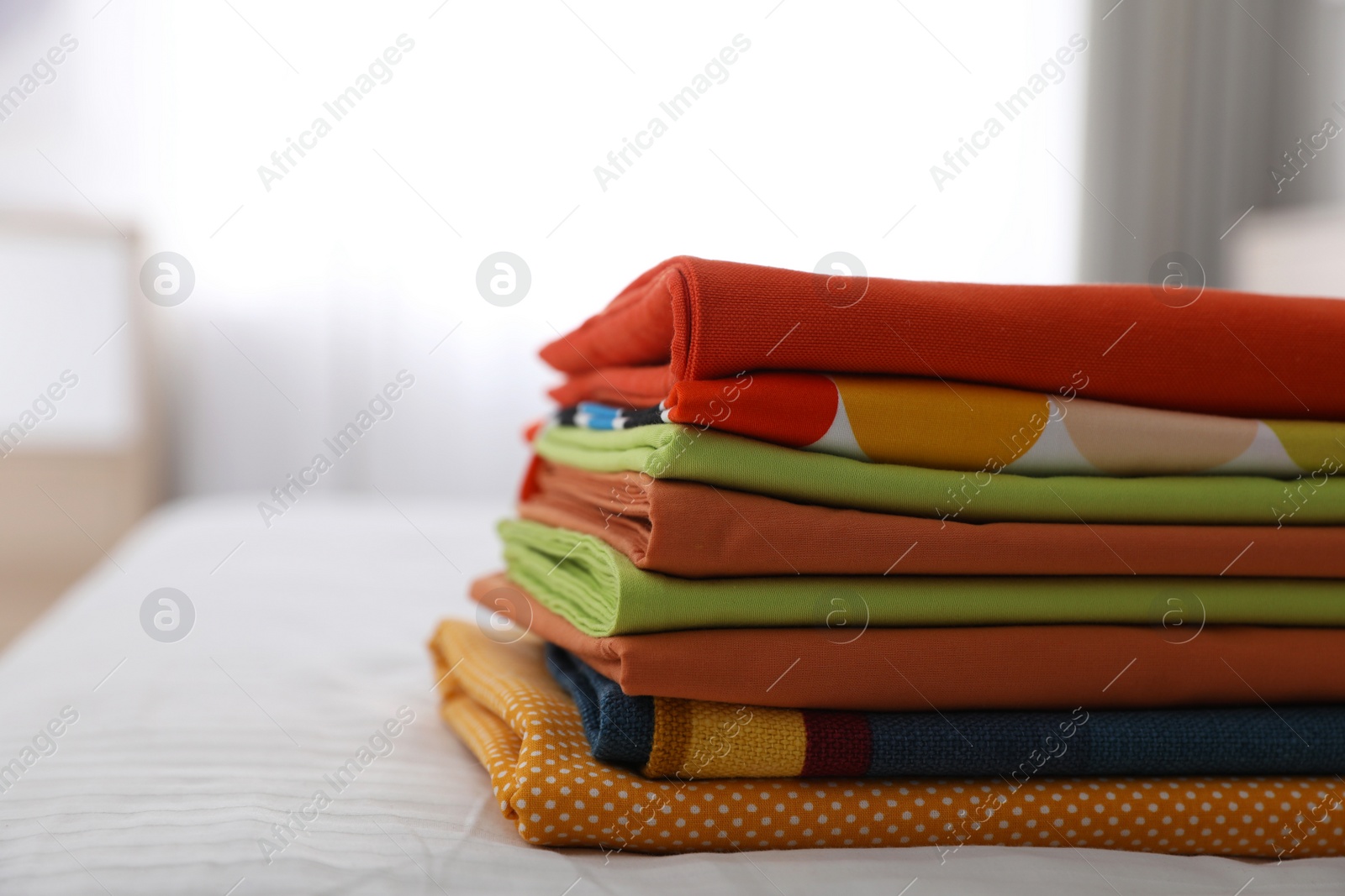 Photo of Clean color folded linens on bed indoors. Space for text