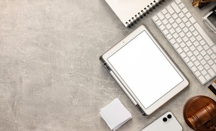 Photo of Flat lay composition with modern tablet on light gray textured table. Space for text