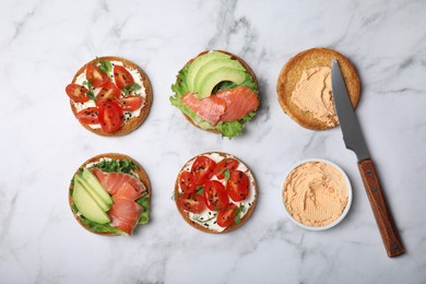 Tasty rusks with different toppings on white marble table, flat lay