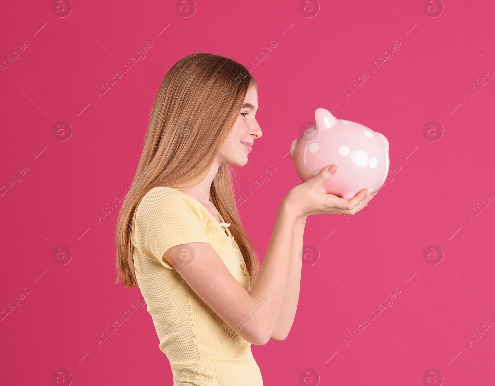 Photo of Teen girl with piggy bank on color background