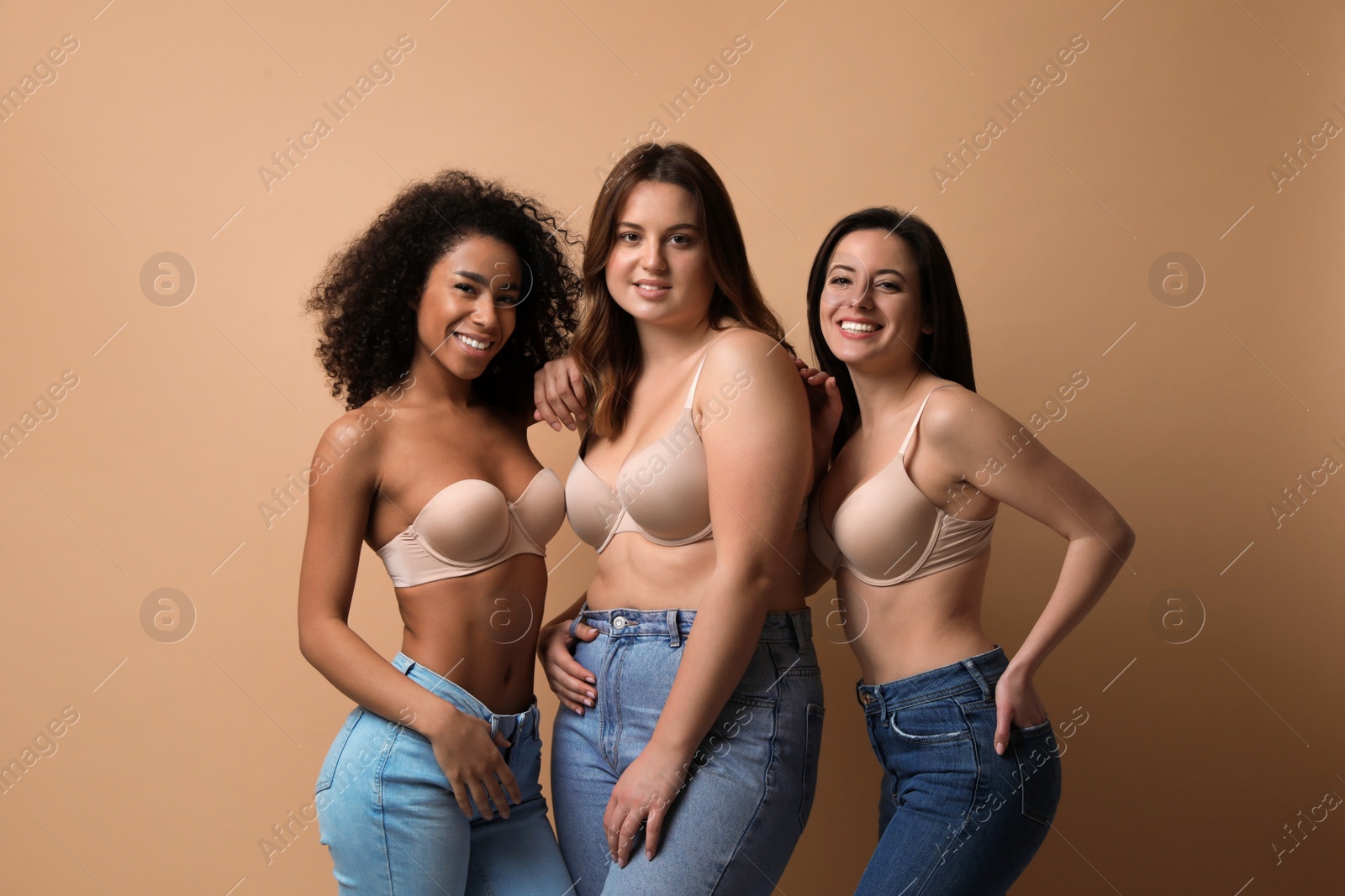 Photo of Group of women with different body types in jeans and underwear on beige background