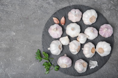 Photo of Slate plate with fresh garlic on gray background, top view