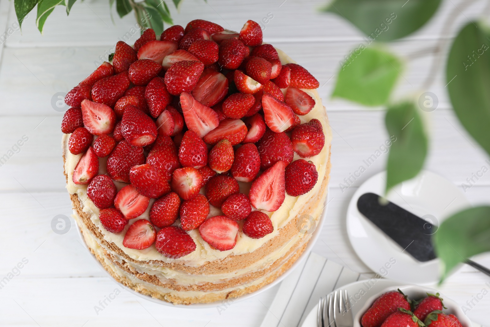 Photo of Tasty cake with fresh strawberries served on white table, above view