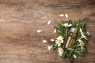 Photo of Flat lay composition with bottle of chamomile essential oil and space for text on wooden background