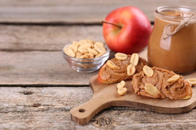 Photo of Fresh apples with peanut butter on wooden table, space for text