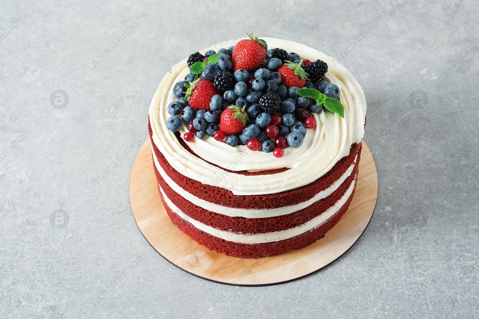 Photo of Delicious homemade red velvet cake with fresh berries on table