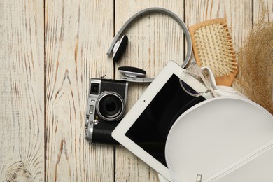 Photo of Stylish urban backpack with different items on white wooden background, flat lay
