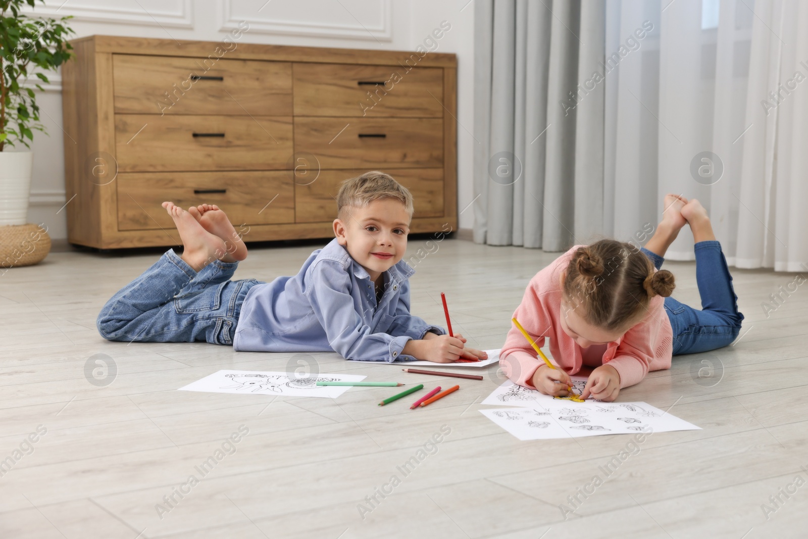 Photo of Cute little children coloring on warm floor at home. Heating system