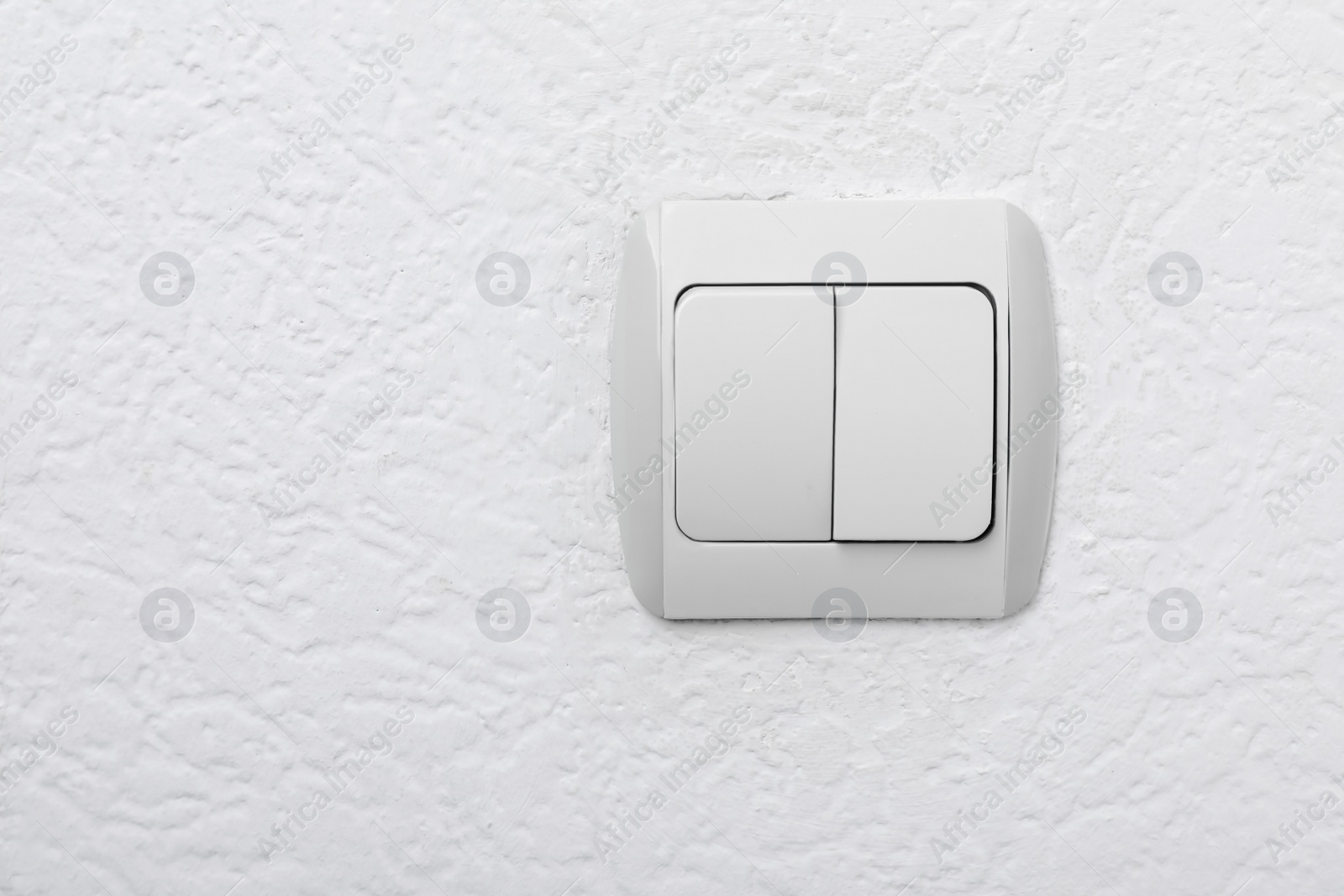 Photo of Modern light switch on white wall. Space for text