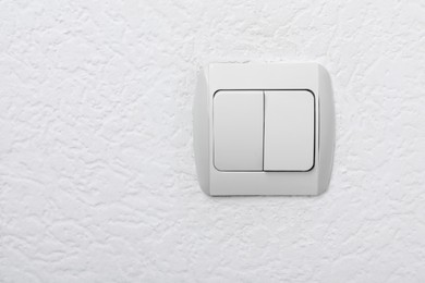 Photo of Modern light switch on white wall. Space for text