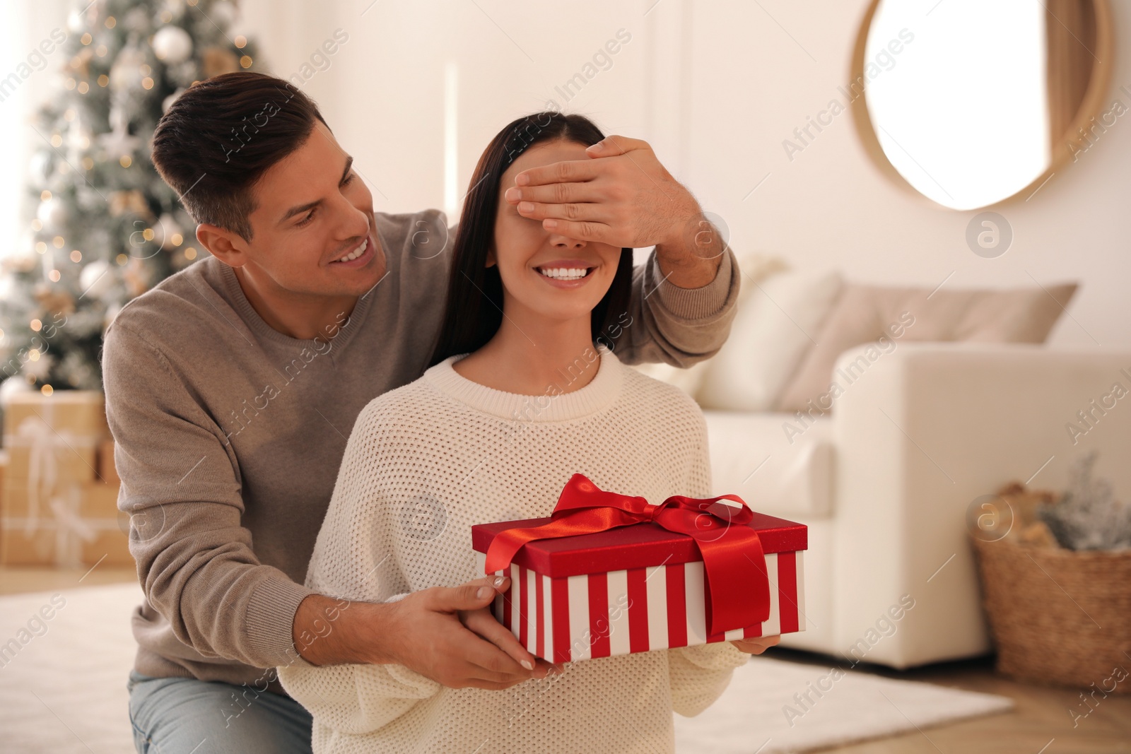 Photo of Boyfriend giving Christmas gift box to his girlfriend in living room