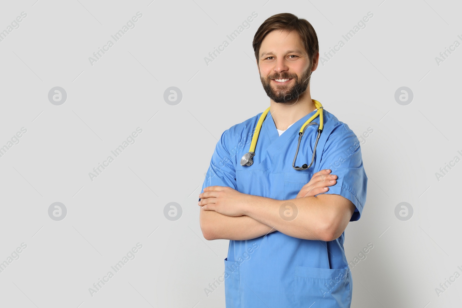 Photo of Doctor or medical assistant (male nurse) with stethoscope on light grey background. Space for text